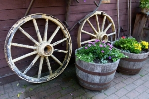 Une déco composée de roues et de fleurs plantées dans des tonneaux en bois